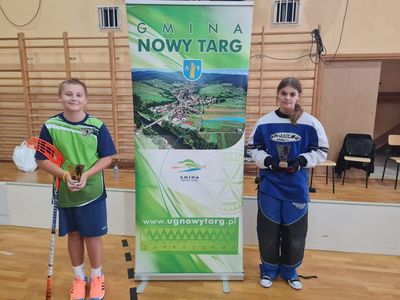 Zawodniczki zawodniczka stojący z pucharami na tle baneru gminy nowy targ